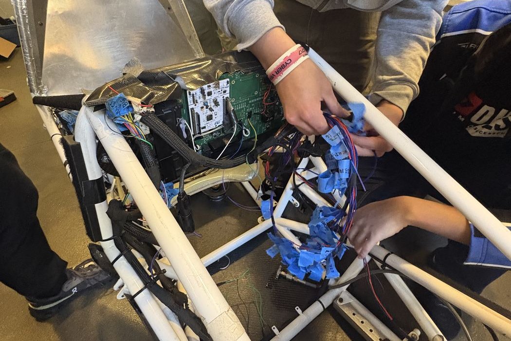 Wiring the low-voltage harness into the car's chassis.